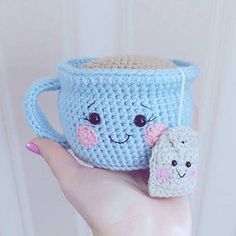 a crocheted coffee cup with a smiling face on it and a small stuffed animal