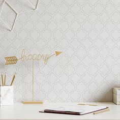 a desk with a notebook, pen holder and gold arrow on it that says happy