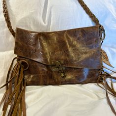 Inherited Leather Boho Style Fringed Brown Envelope Bag. This Bag Features A Long Braided Leather Strap Which Gives You The Option To Wear This On The Shoulder Or Crossbody. The Clasp Is Also Super Unique, And The Leather Fringe On The Sides Of The Bag Keep This Bag Young And Cool. The Inside Is The Other Side Of The Leather And Is Unlined, And The Bag Has Aged Gold Brassy Hardware Throughout. The Leather Itself Also Has And Embossed Pattern That Adds Even More Flair To This Bag. Inherited Leather Is Based Out Of Louisville, Kentucky And Repurposes And Up-Cycles Old Leather Goods In To One-Of-A-Kind, Unique, Modern Pieces. So Much Better For The Environment Than Buying New! H 7.75” W 11.5 Embossed Pattern, Brown Envelope, Boho Fringe, Louisville Kentucky, Brown Envelopes, Envelope Bag, Leather Fringe, Braided Leather, Leather Goods