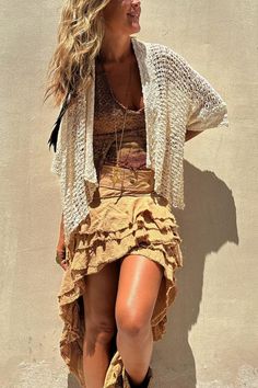 a woman is standing against a wall with her legs spread out, wearing boots and a sweater