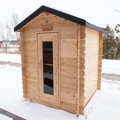 a wooden outhouse sitting on top of snow covered ground