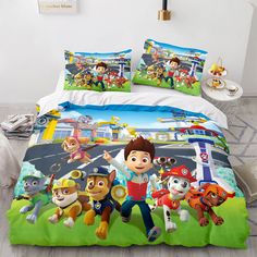 a bed with paw patrol comforter and pillow cases on top of it, in front of a white wall