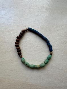 a beaded bracelet with blue and brown beads on a white surface, resting on a table