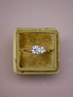 an engagement ring in a velvet box with two diamonds on the top and one diamond at the bottom