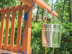 a metal bucket hanging from a wooden deck next to a roped in planter