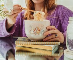 a woman eating noodles from a bowl with chopsticks