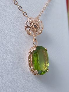 This Edwardian pendant necklace is set with a light natural green peridot. There is delicate floral rose gold filigree surrounding the gem. This lovely reproduction of fine antique filigree jewelry has a full cut oval stone that sparkles with movement while catching the eye. Lovingly crafted by Silver Embrace Jewelry Luxury Peridot Jewelry For Gifts, Elegant Formal Necklace With Peridot, Elegant Peridot Necklaces For Wedding, Elegant Peridot Jewelry For May Birthstone, Elegant Jewelry With Intricate Design For May Birthstone, Elegant May Birthstone Jewelry With Intricate Design, Formal Peridot Pendant Necklace, Elegant Peridot Necklace For Gift, Goddess Crystals