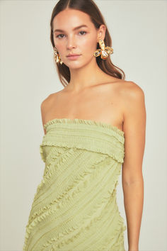 a woman in a green dress with gold earrings