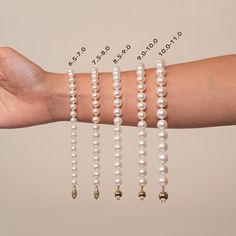 a woman's arm with four bracelets and three pearls on the wrist, all in different shapes and sizes