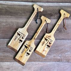 three wooden spoons with animals on them sitting next to each other in front of a wood background