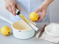 a person grating lemons into a bowl with a grater on the counter