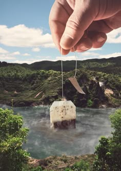 a hand holding a piece of paper with a knife stuck to it in the middle of a river