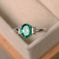 an emerald and diamond ring in a box