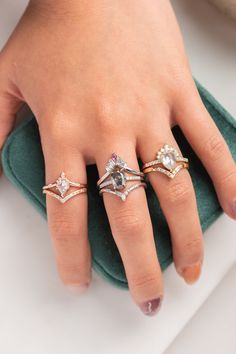 a woman's hand with three different rings on her finger and one is wearing a ring