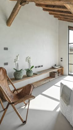 a living room filled with furniture next to a window covered in white sheets and pillows