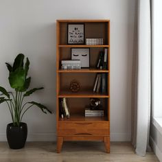 a wooden bookcase next to a potted plant in a room with white walls