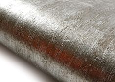 a roll of metallic foil with red highlights on the bottom and sides, laying flat against a white background