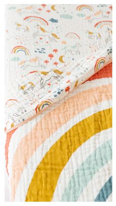 an unmade bed with a colorful rainbow quilt on it's bottom and side