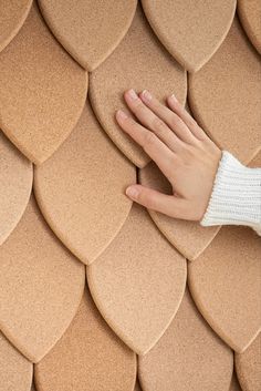 a person's hand on the top of a wall made out of brown tiles