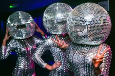 several people in shiny disco suits with their hands on the back of their heads as they dance