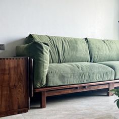 a green couch sitting next to a wooden table and potted plant on top of it