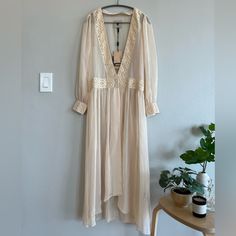 From Free People, One Teaspoon Size S (Eu 36/Us 6), Puff-Sleeved 2-Button Dressing Gown In Beige. Material: 100% Polyester With 100% Cotton Trim. Measurements (Lying Flat): Bust 16”, Waist 17.5”, Length (Front) 45.5”, Length (Back) 51”. Cottagecore Long Sleeve Dress For Brunch, Beige Long Sleeve Maxi Dress For Garden Party, Vintage Beige V-neck Maxi Dress, Beige Maxi Dress With Lace Trim For Daywear, Beige Lace Trim Maxi Dress For Daywear, Beige Long Sleeve Maxi Dress With Lace Trim, Beige Maxi Dress With Lace Trim For Brunch, Vintage Lace Trim Dress For Brunch, Cream Long Maxi Dress For Daywear