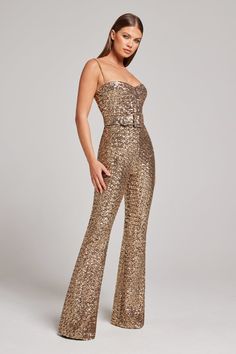 a woman in gold sequin jumpsuits posing for the camera with her hands on her hips