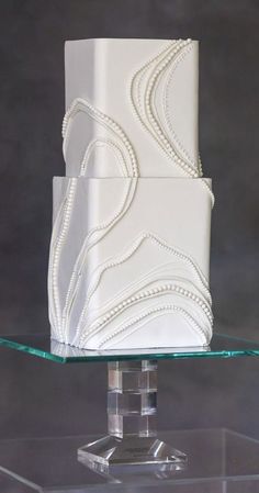 a three tiered white wedding cake sitting on top of a glass stand