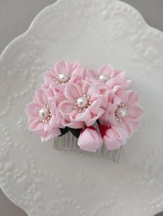 a pink flower hair comb with pearls on it's head sits on a white plate