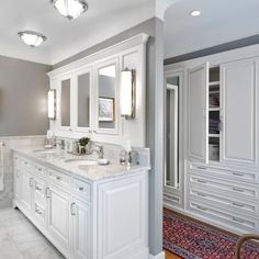 a bathroom with two sinks, mirrors and cabinets in white marble counter tops on either side of the bathtub