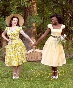 two women in dresses and hats holding hands