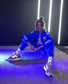 a woman is sitting on the ground with her feet up and wearing adidas sneakers