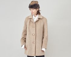 "Beige Lama Wool Coat for Women Size L - XL | Warm Winter Coat Stay warm and stylish with this vintage 100% lama wool coat with pockets, perfect for women in sizes L - XL. Designed with raglan sleeves, this coat features pockets and beautiful matching buttons. The coat has a minimalist design, making it a timeless piece in any wardrobe. The coat's measurements when lying flat are: armpit to armpit - 56 cm | 22\", length - 82 cm | 32.3\", sleeves - 74 cm | 29\" (from collar down). It is in excellent condition, with no flaws and is shown on a size S model, 1,68 m | 5.5 ft tall. It was not pinned for the pictures. Pair this coat with our custom-made black wool pants, tuxedo style for a chic winter look. Our shop is dedicated to curated vintage and handmade clothing, using only fine fabrics. C Classic Beige Fur Coat For Workwear, Classic Fur Coat For Work In Fall, Classic Long Sleeve Beige Fur Coat, Classic Beige Long Sleeve Fur Coat, Classic Fur Coat With Pockets For Fall, Classic Wool Fur Coat With Long Sleeves, Blue Cashmere Sweater, Handmade Pants, Winter Overcoat