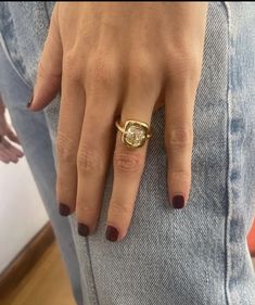 a woman's hand wearing a gold ring with a diamond in the middle and on her finger