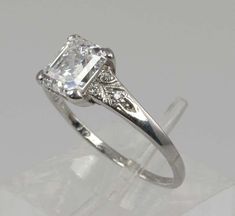 an engagement ring with a princess cut diamond in the center and filigrees around the band