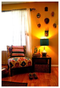 a living room filled with furniture next to a window covered in sun shining through the curtains