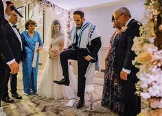 a group of people standing next to each other in front of a bride and groom