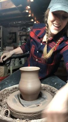 a woman making something out of clay on a potter's wheel