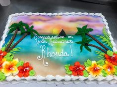 there is a cake that has been decorated with flowers and palm trees on the beach