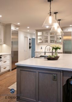 a large kitchen with an island in the middle and two pendant lights hanging from the ceiling