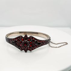 A very fine Antique Bohemian gold-filled bangle bracelet.   Prong set with garnets in a flower pattern to the top and around the circumference of the bracelet.   The bracelet opens at the middle on a hinge and is secured by both a box clasp and safety chain.  Simply a wonderful piece!  Date: 19th Century  Overall Condition: It is in overall good, as-pictured, used estate condition. There are two small garnets missing from top of flower pattern, some very fine & light surface scratches and other Victorian Jewelry Bracelet With Jewels, Heirloom Gemstone Bangle Bracelets, Heirloom Gemstone Bangle Bracelet, Victorian Bangle For Ceremonial Occasions, Garnet Bangle Jewelry Gift, Garnet Bangle Jewelry As Gift, Victorian Ceremonial Bangle Jewelry, Garnet Gemstone Bracelet Jewelry, Ornate Hinged Bangle Bracelets