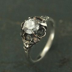 a close up view of a ring with an oval stone in the center and flowers on it