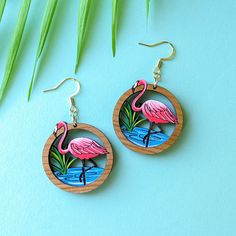 These unique flamingo round dangles are miniature works of art with 2 layers of cherry wood creating a framed vignette of this beautiful bird in its natural habitat. This original design features delicately etched and hand-painted details in a vibrant palette of pink and white, aqua and grass green. The vibrant colors are framed in round cherry wood which creates a a miniature diorama. These earrings are lightweight and durable and make a one-of-a-kind statement for flamingo lovers, birders, gardeners, or anyone who loves nature. Get ready for compliments!Option #1: Painted Wood RoundsThese earrings feature painted cherry wood rounds with hypoallergenic gold-finished, 304 stainless steel studs and butterfly backs. Drop Length: 2"Option #2: Gold Ear WiresThese earrings feature hypoallergeni