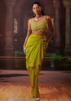 Featuring a beautiful lime green silk embroidered crop top that showcases a stunning array of mirrors and studs, paired with a stylish bandhani lime green silk cape featuring intricate embroidery along its sleeves. Complete your look with a heavy drape saree and a matching potli for a truly captivating and stylish outfit. A perfect indo western silhouette pick for family gathering and mehendi ceremony. Composition : Blouse, Skirt, Outer cape and Saree - Silk Care: Dry Clean Only and Vacuum Storage This product can be customized for sleeves, length of blouse and neckline Delivery : 6-8 weeks as the product is hand crafted. Check Size Guide or choose MySize for free customisation (All Sizes above XL can be made at 15% additional cost) For more information and sizes please contact fabilicious Green Embellished Traditional Wear For Navratri, Green Embellished Sets For Navratri, Embellished Green Traditional Wear For Navratri, Embellished Pista Green Georgette Pre-draped Saree, Embellished Pista Green Pre-draped Saree In Georgette, Green Embellished Designer Traditional Wear, Festive Green Georgette Top, Festive Green Embellished Choli, Festive Embellished Green Choli