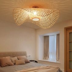 a bed room with a neatly made bed and a light fixture hanging from the ceiling