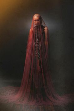 a woman with long red hair and veil on her head is standing in the dark