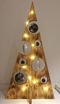 a wooden christmas tree with lights on it's sides and ornaments hanging from the top