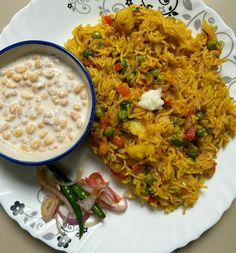 a white plate topped with rice and veggies next to a bowl of soup