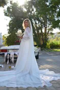 a woman in a wedding dress standing next to a car