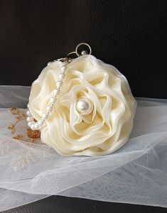 Elevate your special occasion look with this elegant Ivory Organza Flower Evening Clutch Bag. Perfect for brides or bridesmaids, this exquisite handbag features a delicate pearl handle that adds a touch of glamour to your ensemble. Whether you're attending a wedding or a formal event, this beautiful pouch is the perfect accessory for ladies who appreciate timeless sophistication and style. Stand out from the crowd and make a statement with this stunning evening clutch bag. Colour: light gold wit Elegant Flower-shaped Evening Bag, Elegant Cream Handheld Evening Bag, Elegant Flower Shaped Clutch For Formal Occasions, Elegant Flower Shaped Evening Bag For Gifts, Elegant Flower Shaped Evening Bag For Events, Elegant Flower-shaped Evening Bag For Events, Elegant Flower-shaped Evening Bag For Gifts, Elegant Flower Shaped Evening Bag, Formal Flower-shaped Evening Bag